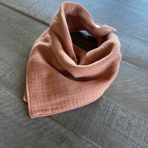 Peut inclure: Une bavette bandana en mousseline de couleur terre cuite avec une fermeture à pression.