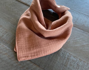 Può includere: Un bavaglino bandana in mussola color terracotta con chiusura a pressione.