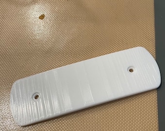 May include: White plastic rectangular plate with two holes. The plate has a textured surface.