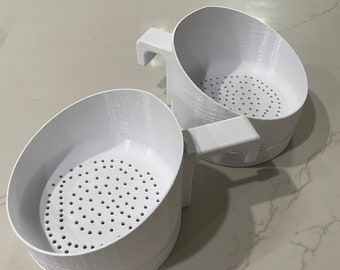 May include: Two white plastic kitchen strainers with handles. The strainers have a mesh bottom with small holes.