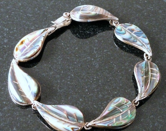 May include: A silver bracelet with a series of iridescent abalone shell leaf charms. The leaves are a teardrop shape with a silver outline and a textured surface.