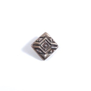 May include: A silver square-shaped button with a geometric design.
