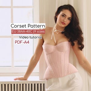 May include: A pale pink corset with a sweetheart neckline and vertical seam detailing. The image includes text that reads "Corset Pattern EU 38AA-40C | 9 sizes Video tutorial PDF-A4". The corset is worn with a white skirt.