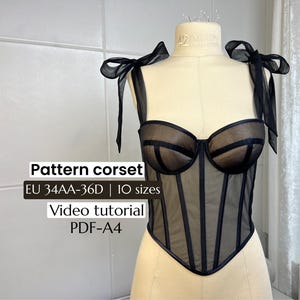 May include: Black corset with sheer panels and structured boning, displayed on a mannequin. The corset features a sweetheart neckline and delicate bow straps. Text on the image reads "Pattern corset" and size information.