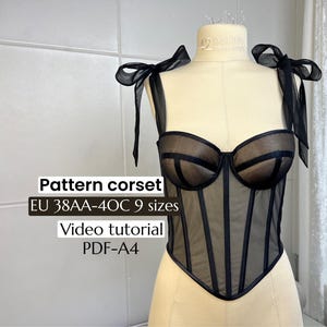 Peut inclure: Corset noir présenté sur un mannequin. Le corset est en résille transparente avec des baleines verticales et un décolleté en cœur. Des nœuds noirs ornent les bretelles. Le texte sur l'image indique "Pattern corset EU 38AA-40C 9 sizes Video tutorial PDF-A4."