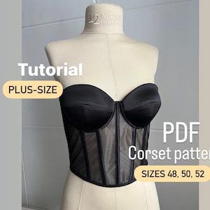 Puede incluir: Un corsé negro sin tirantes con un panel de malla en la parte delantera. El corsé está en un maniquí blanco. El texto "Tutorial PLUS-SIZE PDF Corset pattern SIZES 48, 50, 52" está en la imagen.