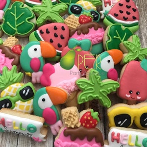 May include: A collection of colorful, decorated sugar cookies in a summer theme. Cookies include toucans, watermelon slices, sunglasses, ice cream, and tropical leaves. Some cookies have the words "Hello Summer" written on them. The cookies are arranged on a light brown wooden surface.