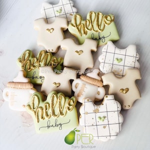 May include: Assortment of decorated sugar cookies with green and white icing. The cookies feature baby-themed designs, including onesies, bottles, and the words "hello baby".
