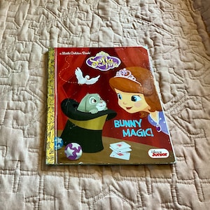 May include: A Little Golden Book featuring Disney's Sofia the First. The cover shows Sofia with a crown, looking at a bunny rabbit in a top hat. The text on the cover reads "Bunny Magic!" and "Disney Junior".