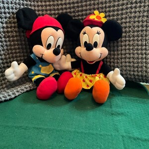 Peut inclure: Une paire de peluches Mickey Mouse et Minnie Mouse. Mickey porte un chapeau rouge et une salopette bleue. Minnie porte un chapeau rouge avec une fleur jaune et une robe &agrave; pois rouges et jaunes.