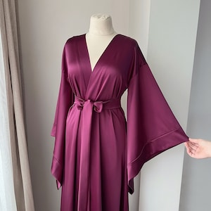May include: A long, deep purple satin robe with wide, flowing sleeves and a tie belt.