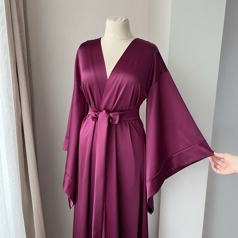 May include: A long, deep purple satin robe with wide, flowing sleeves and a tie belt.