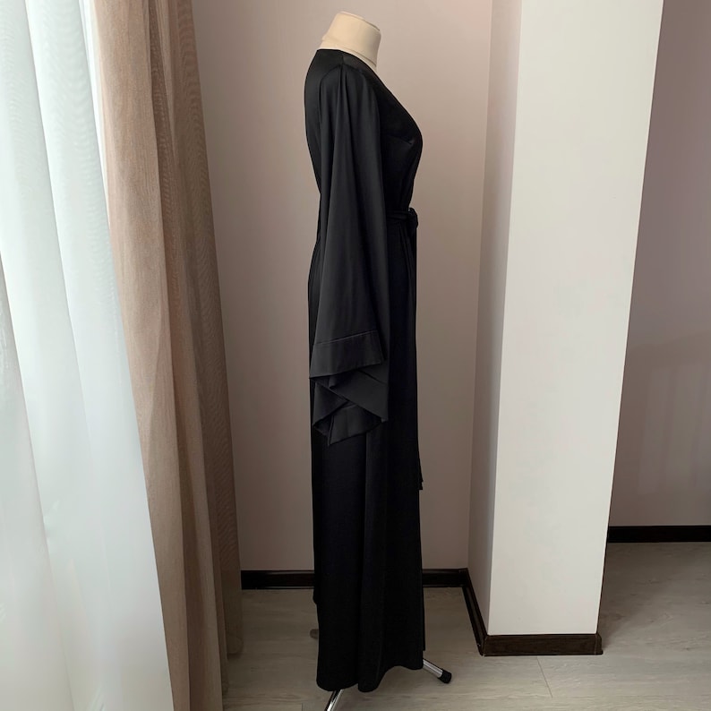 Puede incluir: Una bata larga negra con mangas anchas y cintur&oacute;n a juego. La bata est&aacute; hecha de una tela suave y fluida y se exhibe en un maniqu&iacute;. Las mangas tienen un dise&ntilde;o en capas &uacute;nico. La bata es larga hasta el suelo.