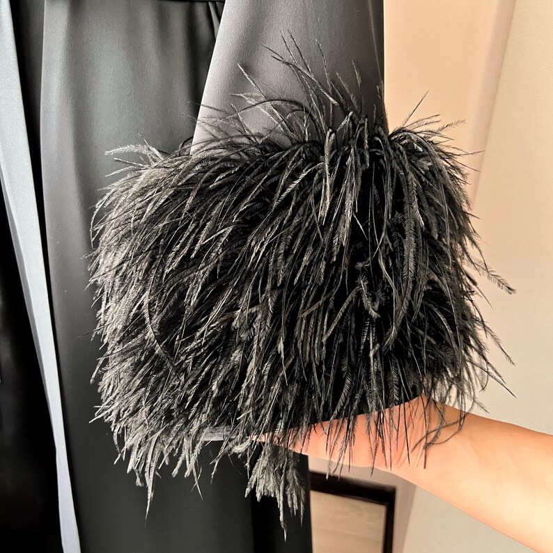 May include: Black satin robe with a black feather trim around the cuffs.
