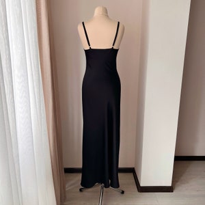 K&ouml;nnte beinhalten: Ein schwarzes, bodenlanges, &auml;rmelloses Schlupfkleid mit geradem Ausschnitt.