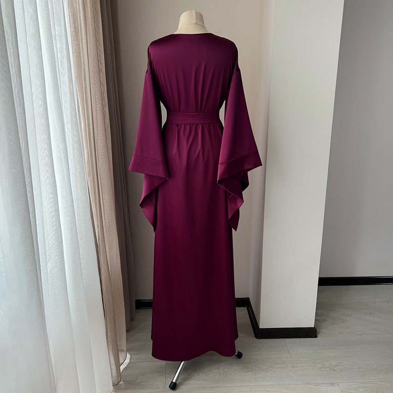 May include: A long, burgundy satin robe with wide, flowing sleeves and a sash tie at the waist.