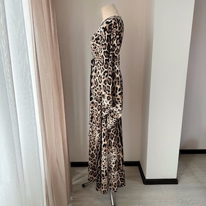 May include: A long-sleeved dress with a leopard print pattern. The dress has a V-neckline and a fitted bodice. The skirt is flowy and has a tiered design.