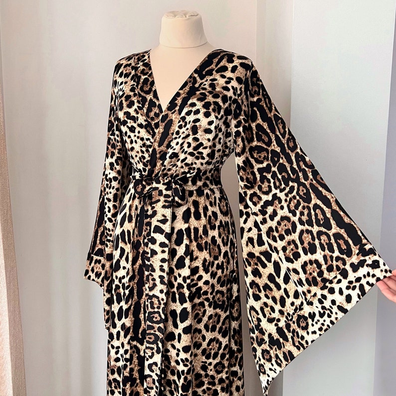 May include: A long-sleeved leopard print robe with a wrap style and a tie belt. The robe has a V-neck and wide bell sleeves.