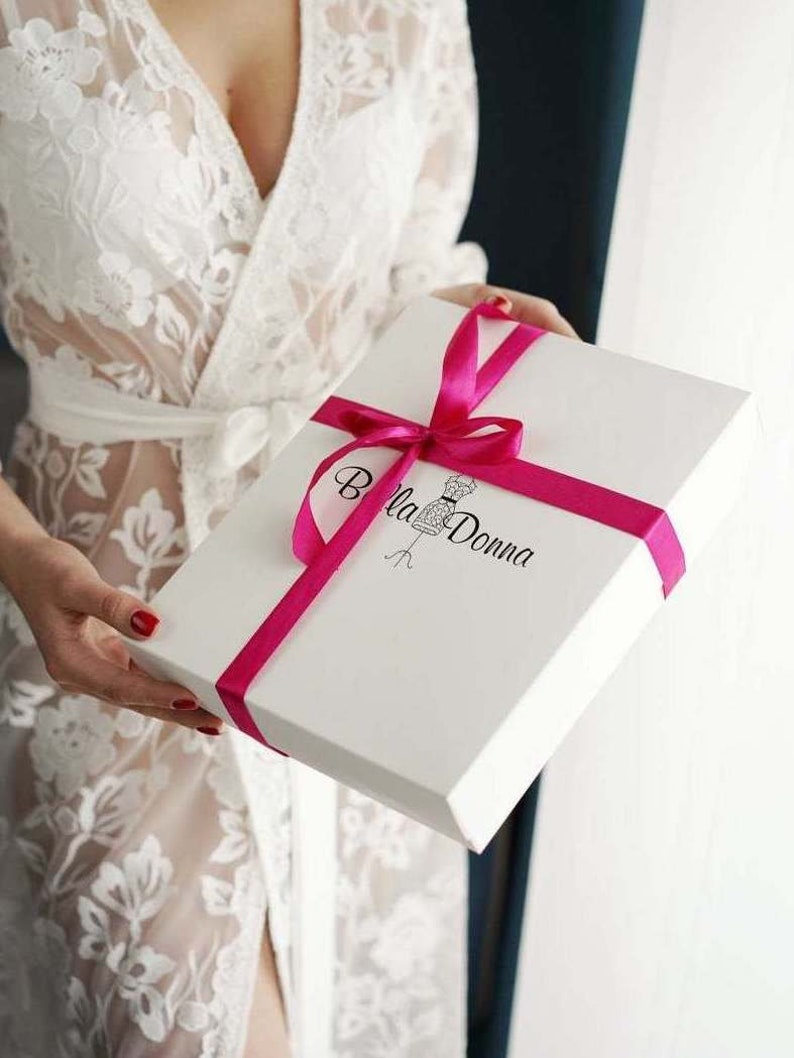 May include: A white gift box with a pink ribbon and the text "Bella Donna" printed on the top.