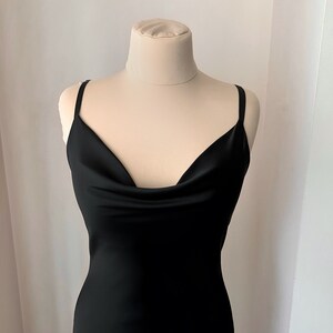 K&ouml;nnte beinhalten: Ein schwarzes, &auml;rmelloses Kleid mit einem Schalkragen und einer figurbetonten Silhouette.
