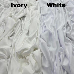 May include: Two fabric swatches, one ivory and one white, are shown side-by-side. The fabric is smooth and has a slight sheen.