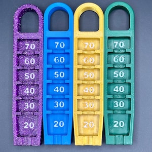 May include: Four plastic measuring tools, each with a different color: purple, blue, yellow, and green. Each tool has a handle at the top and a series of numbers from 20 to 70 printed on the front.