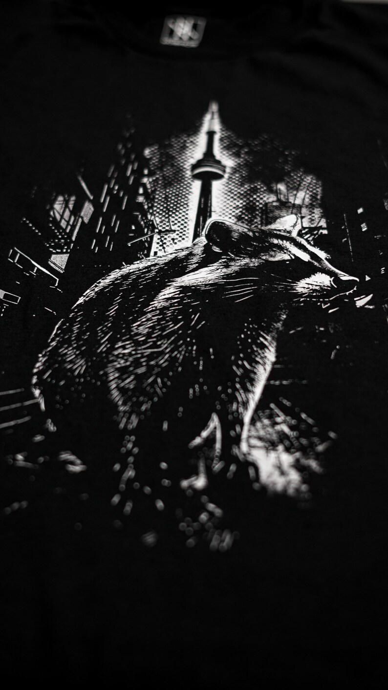 May include: Black and white graphic print of a raccoon walking in front of the CN Tower in Toronto, Canada.