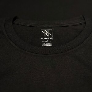 May include: A black t-shirt with a white tag that says "Noir-Noir" and "100% Cotton Assembled in Vietnam of US Components" with a size "M" label.