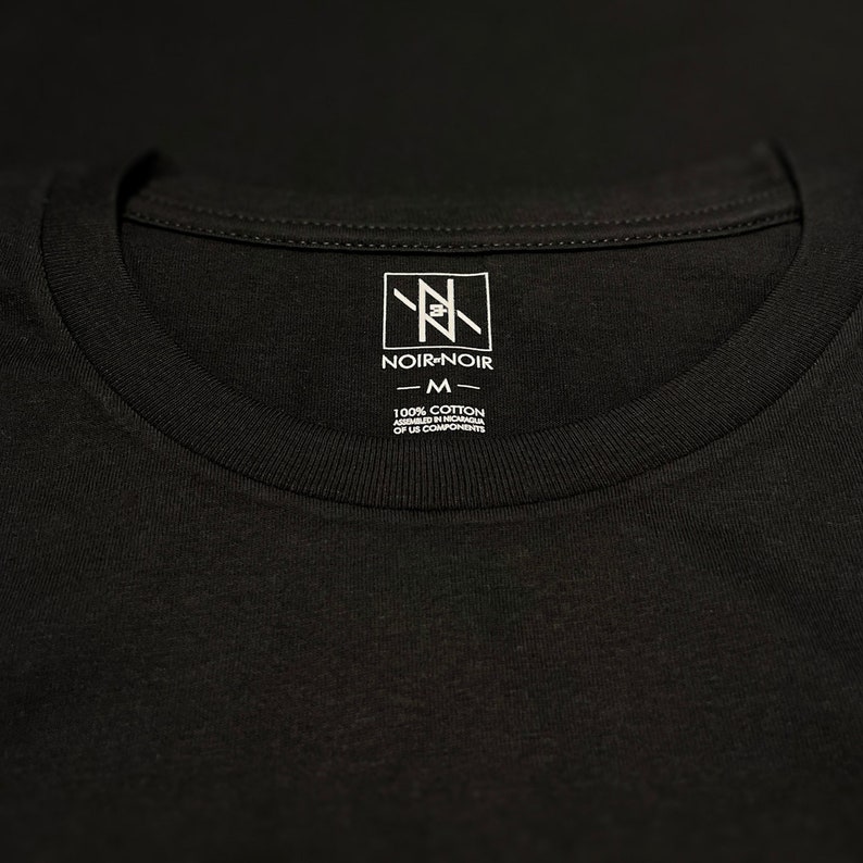 May include: A black t-shirt with a white tag that says "Noir-Noir" and "100% Cotton Assembled in Vietnam of US Components" with a size "M" label.