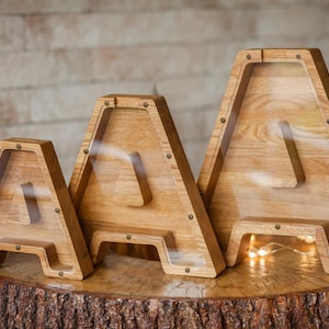 Three wooden letters, likely representing the letters A, B, and C, are displayed on a wooden stump.