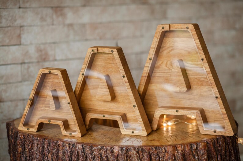Three wooden letters, likely representing the letters A, B, and C, are displayed on a wooden stump.