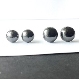 May include: Three pairs of round, black hematite stud earrings. The earrings are small and have a smooth, polished finish.