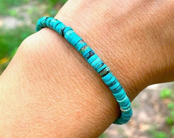 May include: A turquoise beaded bracelet with a simple design. The bracelet is made of small, round beads that are strung together on a thin cord.