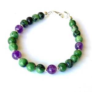 Peut inclure: Une tasse en céramique blanche avec une anse noire et le texte "But First, Coffee" en noir, en gras. La tasse est posée sur une surface blanche.