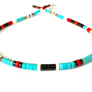 May include: A colourful beaded necklace with turquoise, black, red, white, and brown beads. The necklace has a repeating pattern of beads, creating a vibrant accessory. The beads are strung together to form a circular shape.