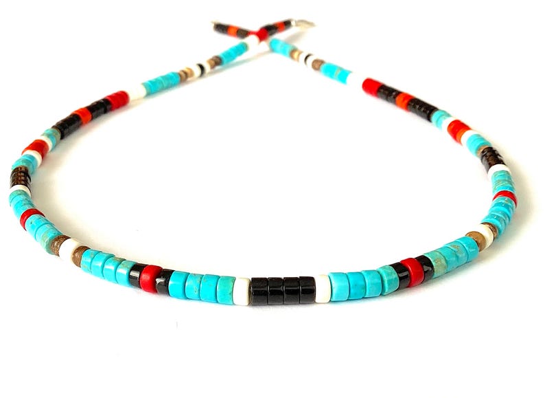May include: A colourful beaded necklace with turquoise, black, red, white, and brown beads. The necklace has a repeating pattern of beads, creating a vibrant accessory. The beads are strung together to form a circular shape.