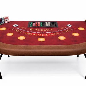 May include: A red and brown blackjack table with a curved edge. The table has a brown padded rim and black metal legs. The table has the text "BLACKJACK" and "INSURANCE PAYS 2 TO 1". There are chips and playing cards on the table.