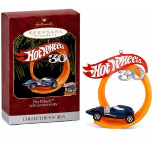 May include: A Hallmark Keepsake Ornament featuring a blue Hot Wheels car on an orange circular track. The red Hot Wheels logo sits above the car with a silver 30. The packaging is a dark red box with the text Hot Wheels 30th Anniversary Collector's Series.