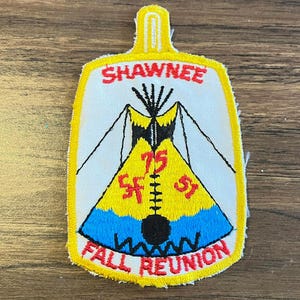 May include: Embroidered patch with a yellow border and a white background. The patch features a teepee design in yellow, blue, and black, with the text "SHAWNEE" and "FALL REUNION" in red. The number "75" is also visible.