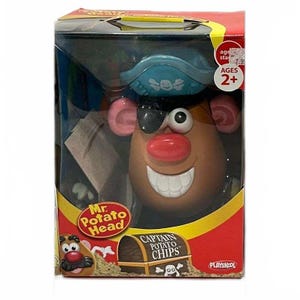 May include: A Mr. Potato Head toy packaged in a box, featuring a brown potato-shaped body with a red nose, white teeth, pink ears, a black eye patch, and a blue pirate hat. The box displays the text Mr. Potato Head and Captain Potato Chips.