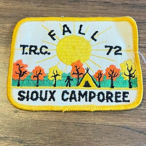 May include: A rectangular embroidered patch with a yellow border featuring a yellow sun, orange and yellow trees, a green field, and a yellow tent. The text reads FALL, TRC, 72, and SIOUX CAMPOREE in black lettering against a white background.