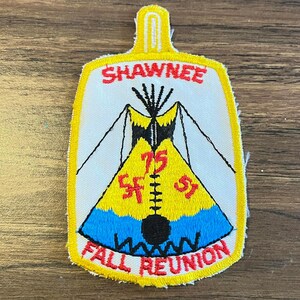 May include: A rectangular embroidered patch with a yellow border and a white background. It features a yellow and blue teepee graphic with black outlines. The text reads SHAWNEE at the top, 75 SF 51 in the center, and FALL REUNION at the bottom.