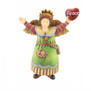 May include: A figurine of an angel with brown curly hair and a gold halo, wearing a green dress with a red plaid top, holding a red heart with the word Peace written in white. The angel has tan wings and a small pocket with orange flowers.