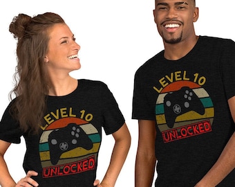 May include: Two black t-shirts with a retro-style graphic of a video game controller and the text "Level 10 Unlocked".
