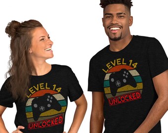 May include: Two black t-shirts with a retro sunset graphic, a video game controller, and the text "Level 14 Unlocked".