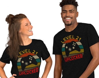 May include: Two people wearing black t-shirts with a retro-style graphic of a video game controller and the text "Level 21 Unlocked".