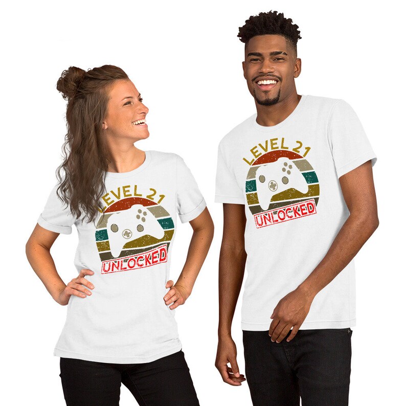 May include: Two white t-shirts with a retro-style graphic of a video game controller and the text "Level 21 Unlocked".