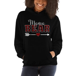 May include: Black hooded sweatshirt with a red and black buffalo plaid design. The text "Mama Bear" is written in white with an arrow and heart graphic.