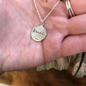 May include: Silver necklace with a round pendant that says "Band L" on the back.