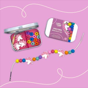 May include: A unicorn bracelet kit in pink and white. The kit contains a tin with beads, unicorn charms, and elastic string. The bracelet is strung with colourful beads and unicorn charms. The tin is labelled "UNICORN BRACELET KIT".